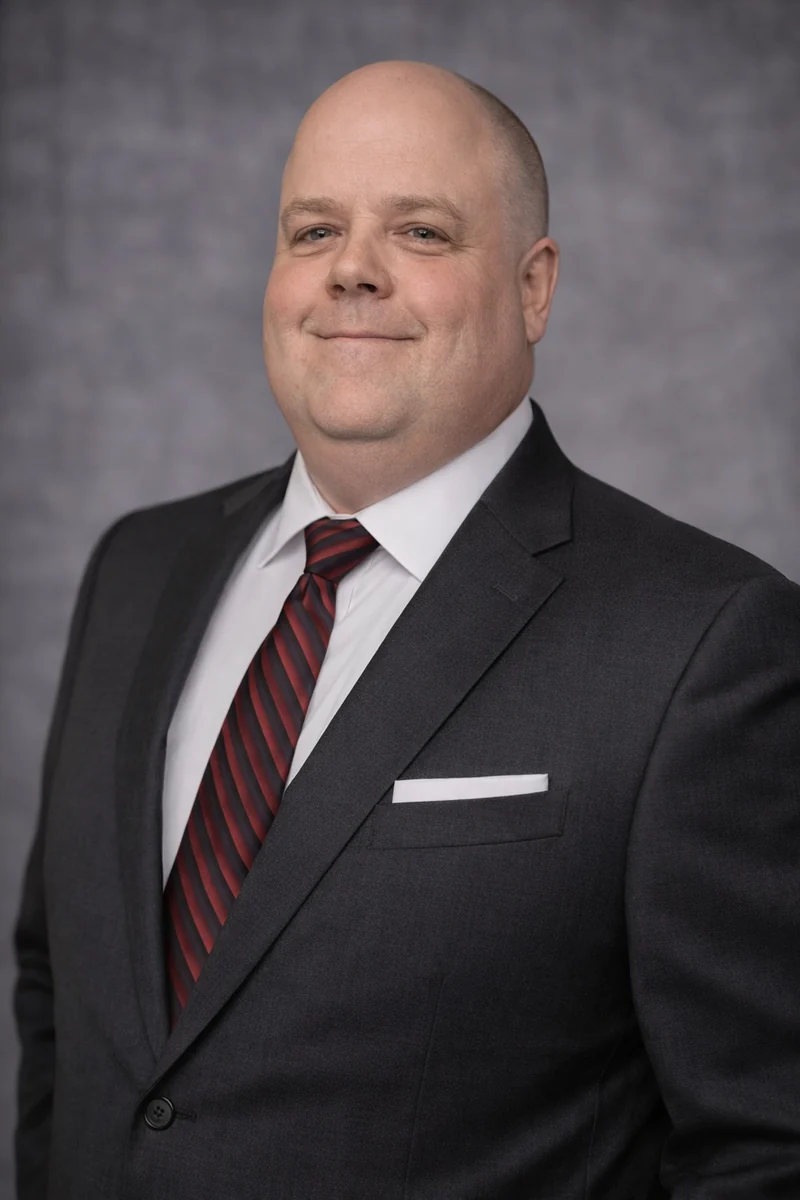 Professional portrait of Brandon Sweitzer in a dark suit and striped tie